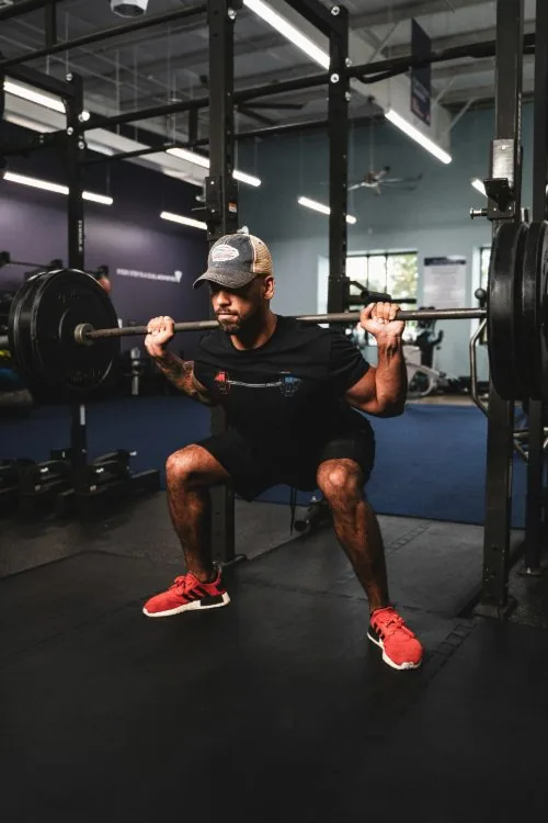 Client performing a barbell squat at the rack